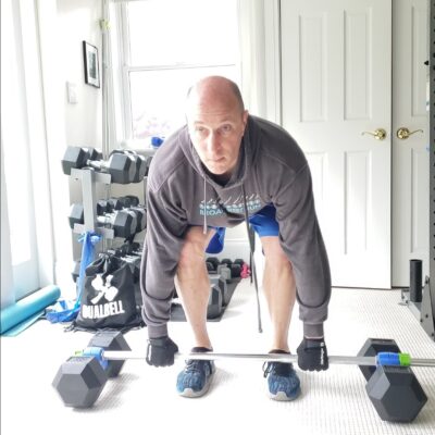exerciser ready to deadlift using dumbbells connected to a barbell by Dualbells